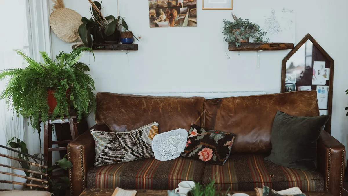 Leather sofa styled with patterned pillows, plants, and rustic wall decor