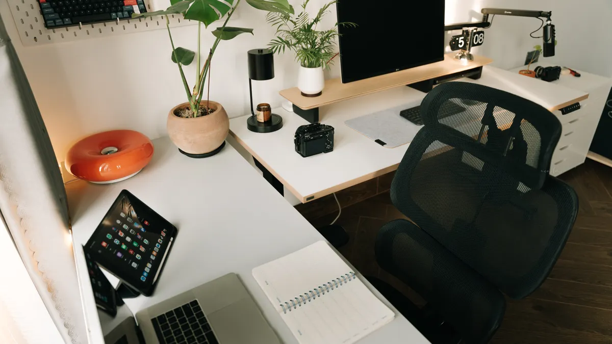Well-styled home office desk with monitor, plants, and chair