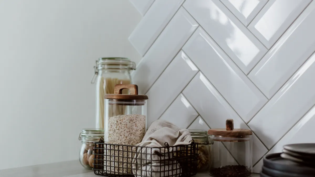 Kitchen counter decor with jars and basket by white tile
